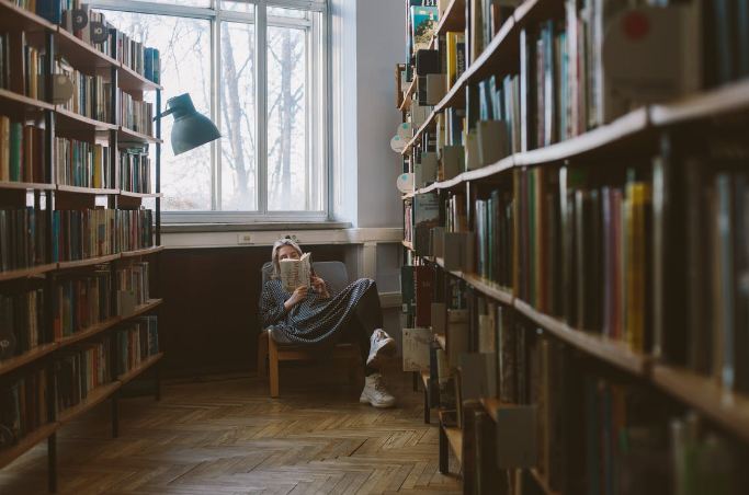 a girl reading a book in a chair in a library