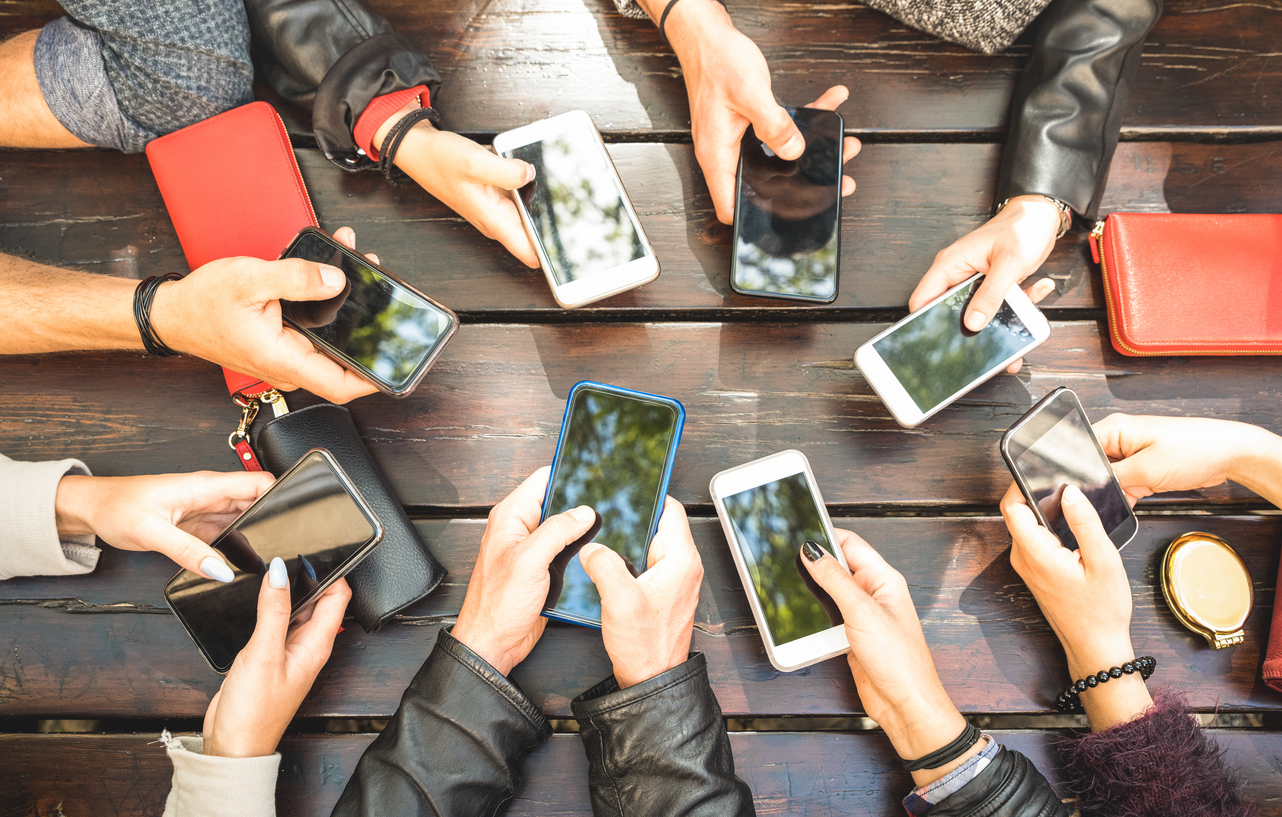 a group of people holding their smartphones, sitting around the table